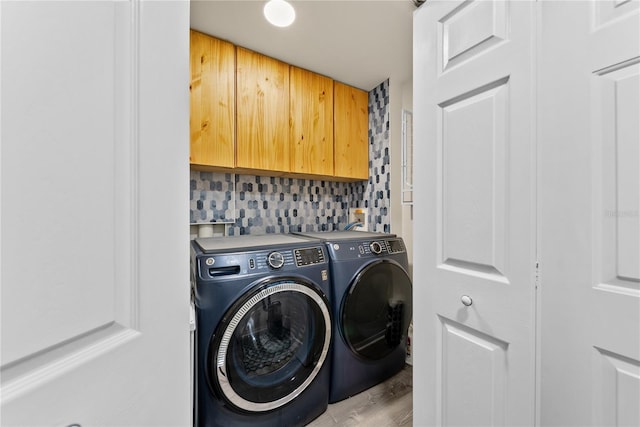 laundry room featuring cabinet space, light wood finished floors, and washing machine and clothes dryer