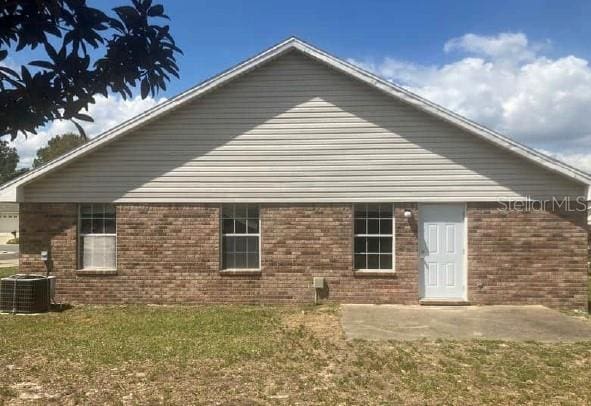 back of property with a patio area, brick siding, central air condition unit, and a lawn