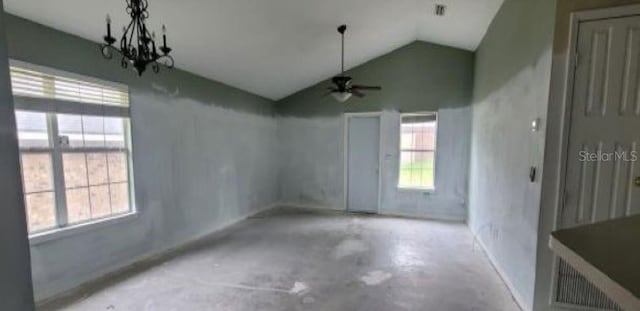 spare room featuring concrete flooring, vaulted ceiling, and ceiling fan with notable chandelier