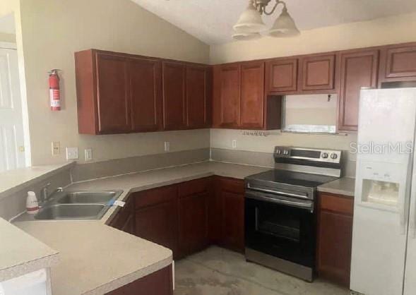 kitchen featuring a peninsula, white refrigerator with ice dispenser, lofted ceiling, and stainless steel electric range oven