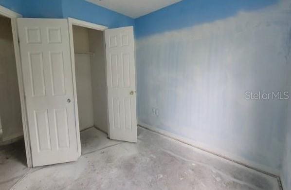 unfurnished bedroom featuring a closet and concrete flooring