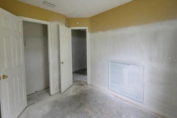 unfurnished bedroom featuring visible vents, unfinished concrete flooring, and a closet