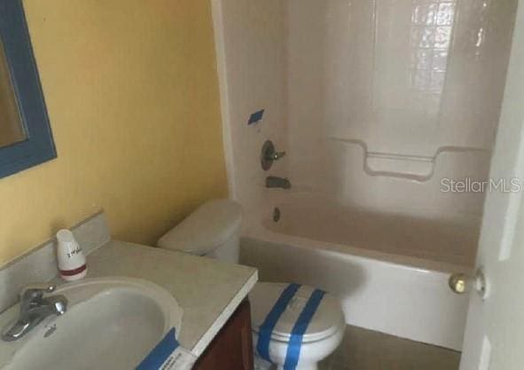 bathroom featuring toilet, vanity, and bathtub / shower combination