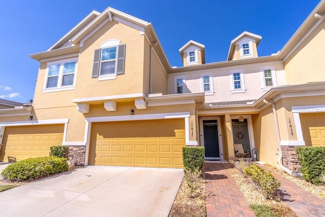 townhome / multi-family property featuring a garage, driveway, and stucco siding