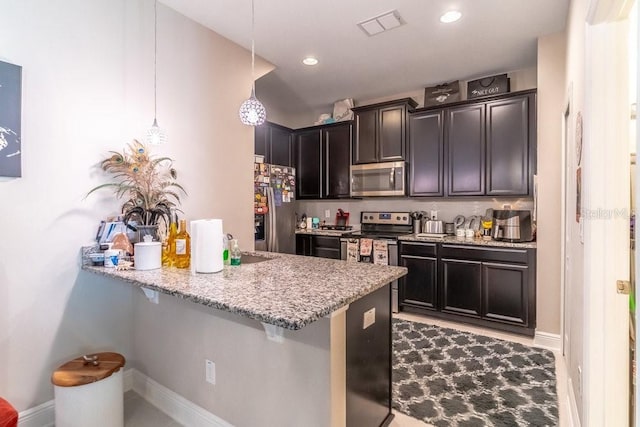 17437 Promenade Dr, Clermont, FL 34711 - kitchen featuring appliances with stainless steel finishes, a kitchen bar, a peninsula, light stone counters, and recessed lighting