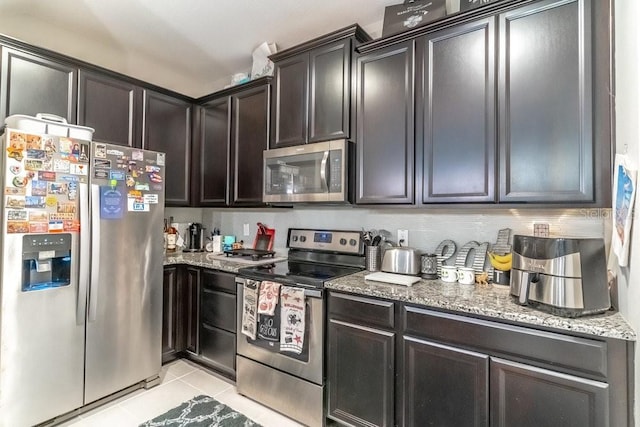 17437 Promenade Dr, Clermont, FL 34711 - kitchen with appliances with stainless steel finishes, light tile patterned floors, light stone counters, dark brown cabinets, and tasteful backsplash