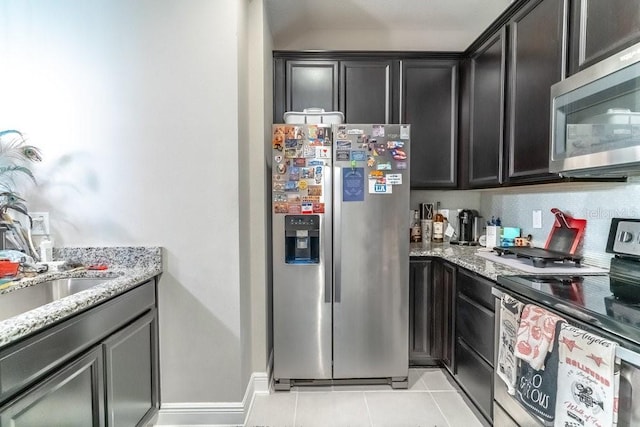 17437 Promenade Dr, Clermont, FL 34711 - kitchen featuring stainless steel appliances, light tile patterned floors, light stone counters, and dark cabinetry