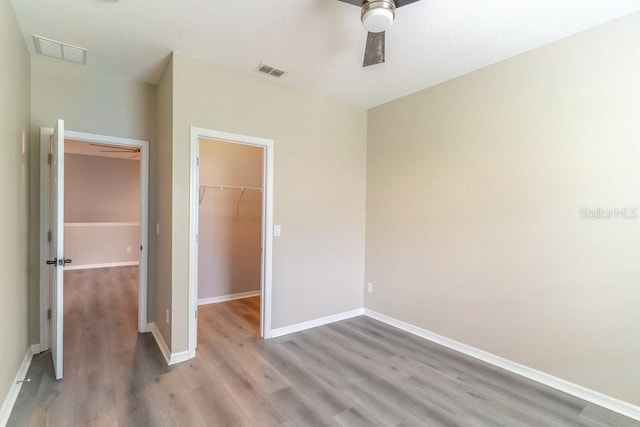 17437 Promenade Dr, Clermont, FL 34711 - unfurnished bedroom with a walk in closet, wood finished floors, a closet, and ceiling fan