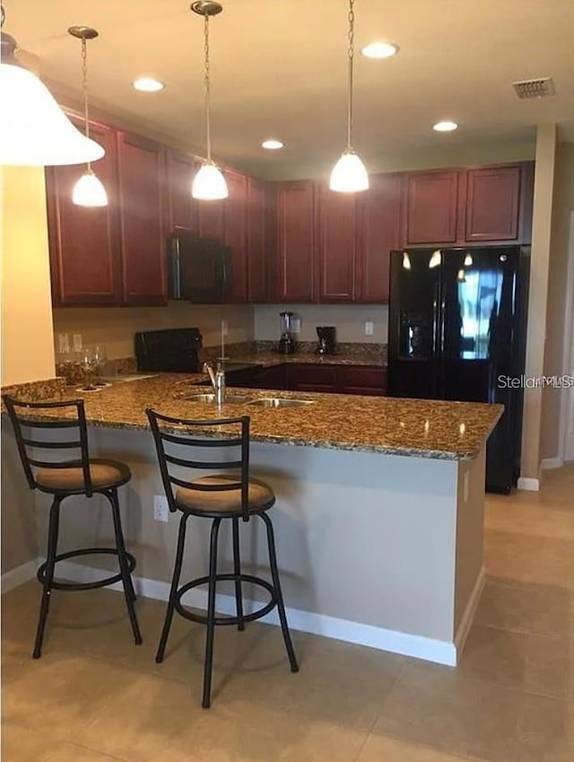 1560 Chelsea Dr, Davenport, FL 33897 - kitchen featuring visible vents, decorative light fixtures, a peninsula, black refrigerator with ice dispenser, and a kitchen bar