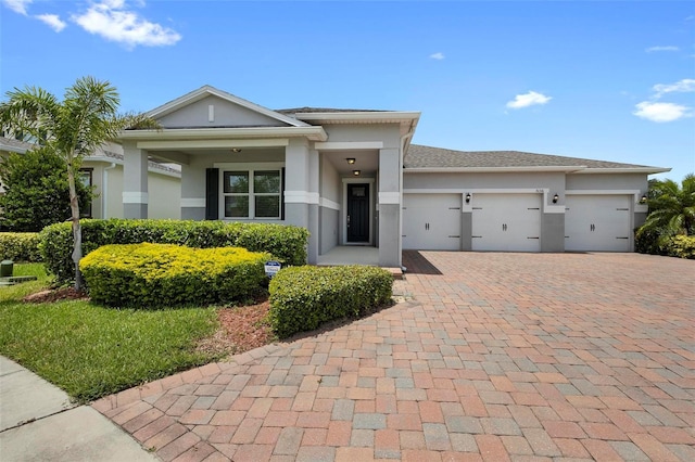 prairie-style house featuring a garage, decorative driveway, and stucco siding