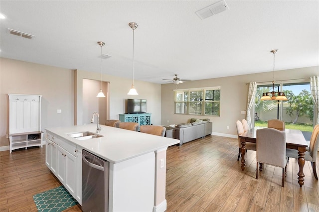 kitchen with a center island with sink, light countertops, stainless steel dishwasher, white cabinetry, and a sink