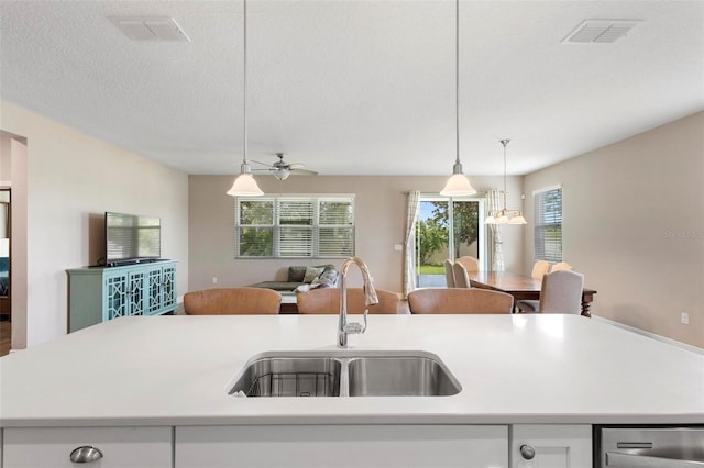 kitchen with a sink, visible vents, open floor plan, light countertops, and an island with sink