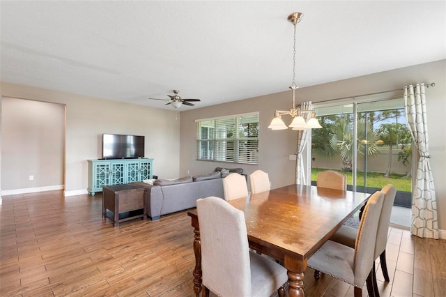 dining space featuring ceiling fan with notable chandelier, light wood finished floors, and baseboards