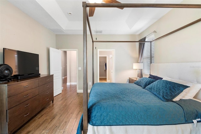 bedroom with ceiling fan, visible vents, baseboards, and wood finished floors