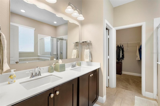 full bath with a stall shower, a walk in closet, a sink, and tile patterned floors