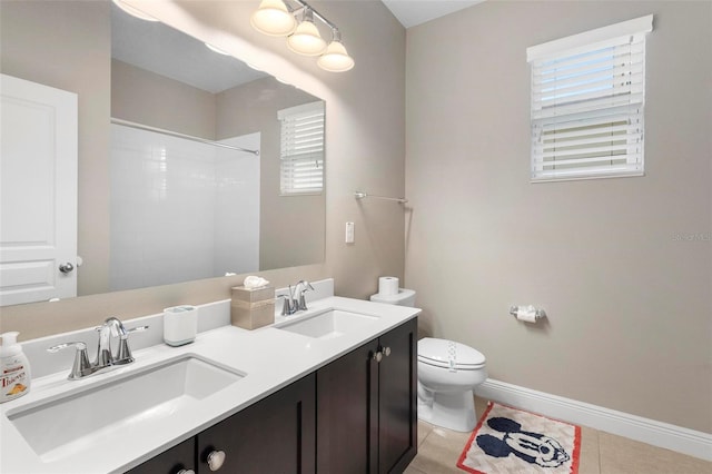 full bath with double vanity, a sink, baseboards, and tile patterned floors