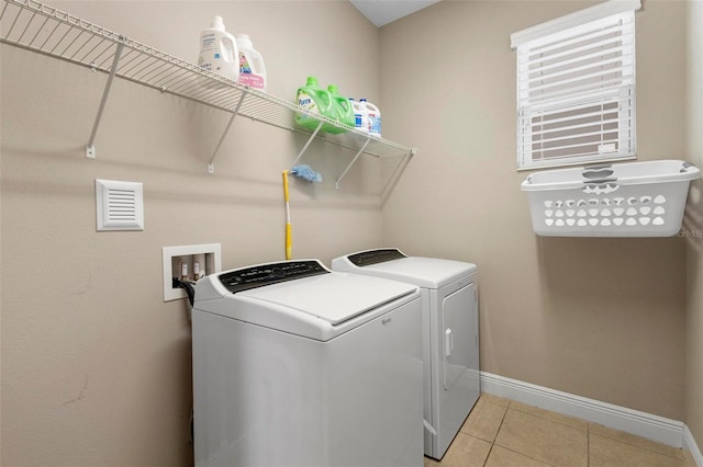 clothes washing area with light tile patterned floors, laundry area, independent washer and dryer, and baseboards