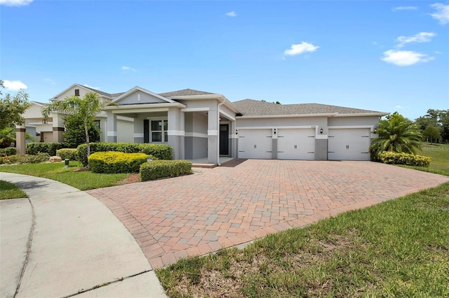 prairie-style house with a garage, a front lawn, decorative driveway, and stucco siding