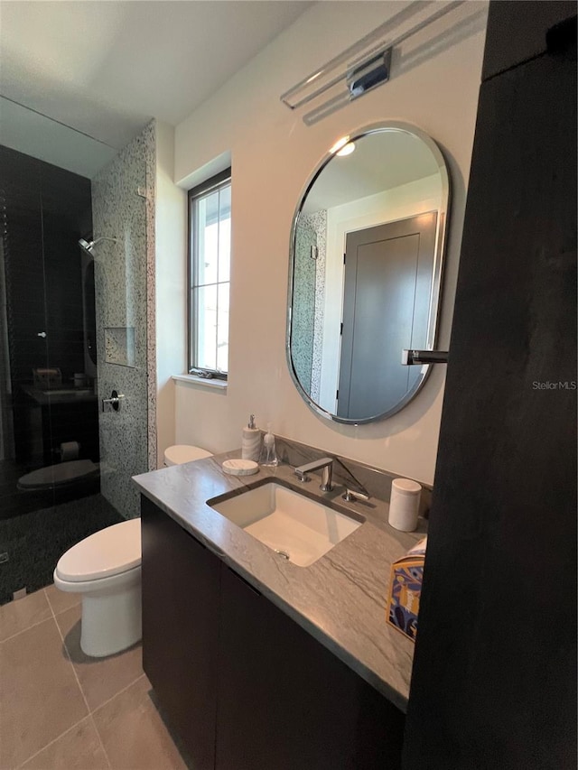 bathroom featuring tile patterned flooring, vanity, toilet, and a walk in shower