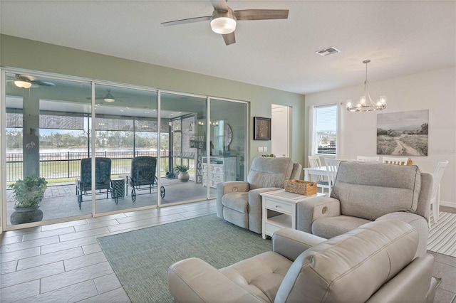 living area featuring wood finished floors, visible vents, and ceiling fan with notable chandelier