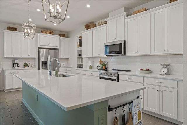 kitchen with white cabinets, a kitchen island with sink, stainless steel appliances, light countertops, and a sink