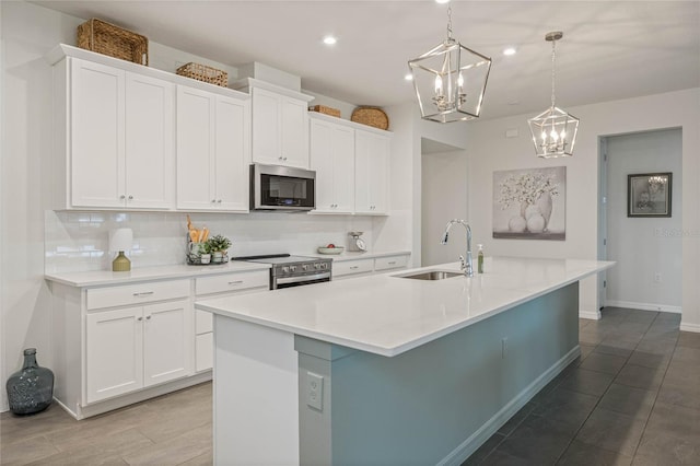 kitchen with a center island with sink, appliances with stainless steel finishes, light countertops, and a sink