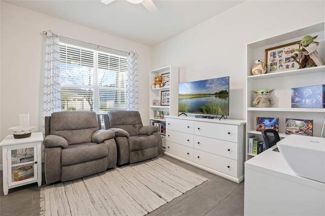 living area with built in shelves and a ceiling fan