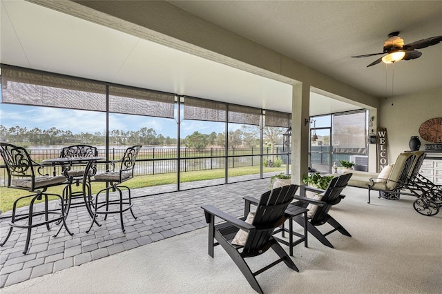 sunroom featuring a water view, plenty of natural light, and a ceiling fan