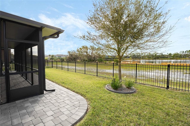 view of yard featuring a water view, a sunroom, a fenced backyard, and a patio