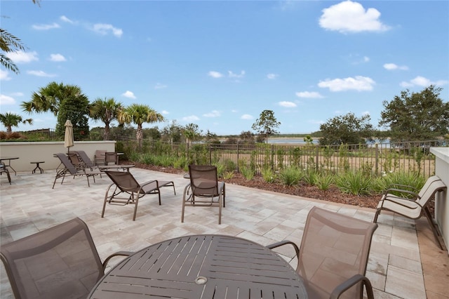 view of patio featuring a water view and fence