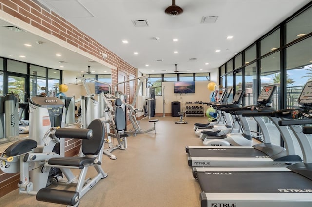 workout area featuring brick wall, recessed lighting, visible vents, and floor to ceiling windows