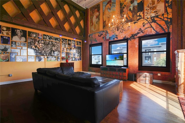 home theater room featuring high vaulted ceiling, a chandelier, baseboards, and wood finished floors