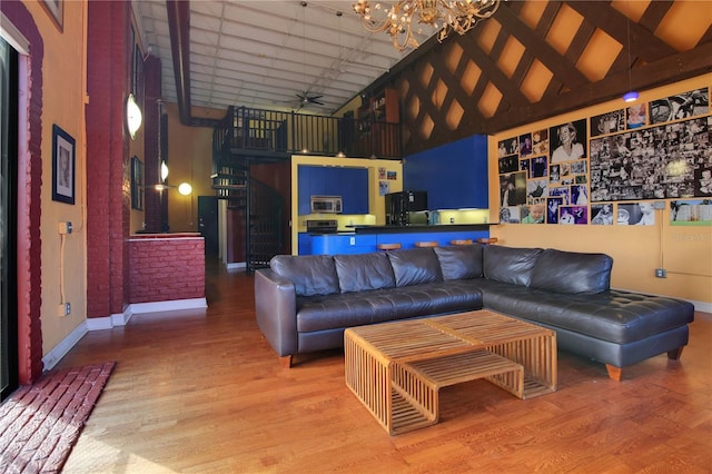 living area with a chandelier, high vaulted ceiling, wood finished floors, and baseboards