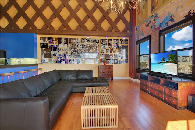 living area with an inviting chandelier, baseboards, a high ceiling, and wood finished floors