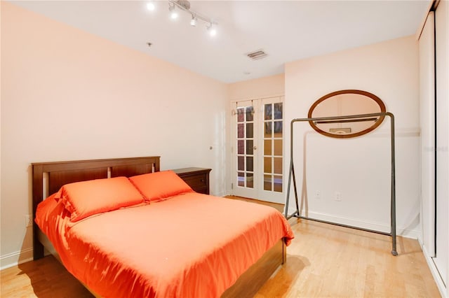 bedroom with french doors, light wood finished floors, visible vents, and baseboards