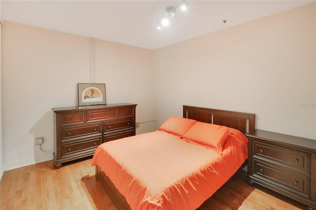 bedroom featuring track lighting, baseboards, and light wood finished floors