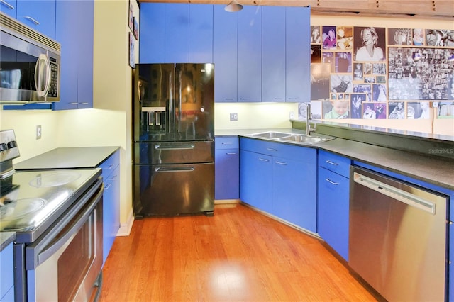 kitchen featuring blue cabinetry, light wood-style flooring, appliances with stainless steel finishes, and a sink