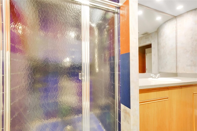 bathroom with a shower with door and vanity