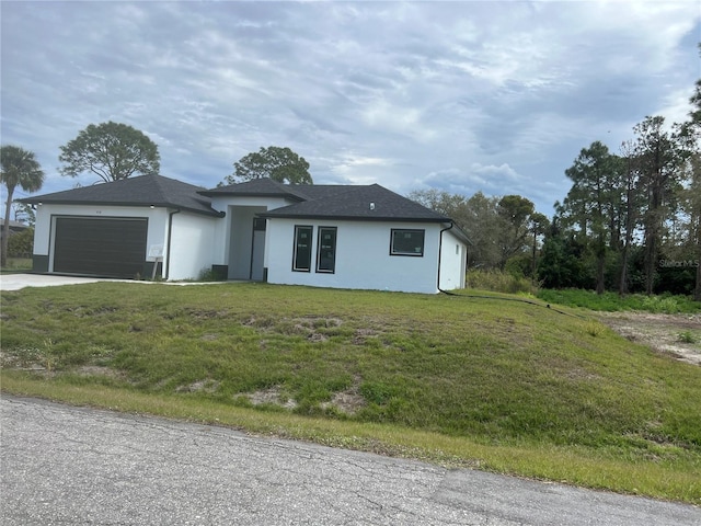 view of front facade with a front lawn, driveway, an attached garage, and stucco siding