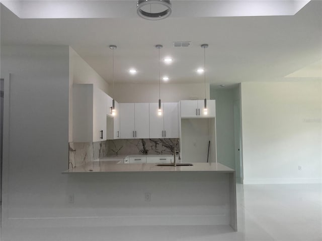 kitchen with a peninsula, pendant lighting, white cabinets, and a sink