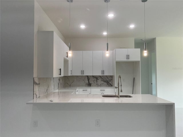 kitchen featuring a sink, white cabinetry, and pendant lighting