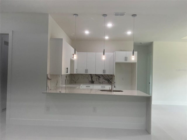 kitchen with visible vents, white cabinets, light countertops, pendant lighting, and a sink