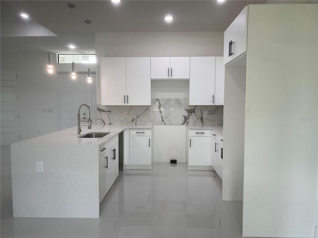 kitchen featuring tasteful backsplash, light stone countertops, marble finish floor, white cabinetry, and a sink