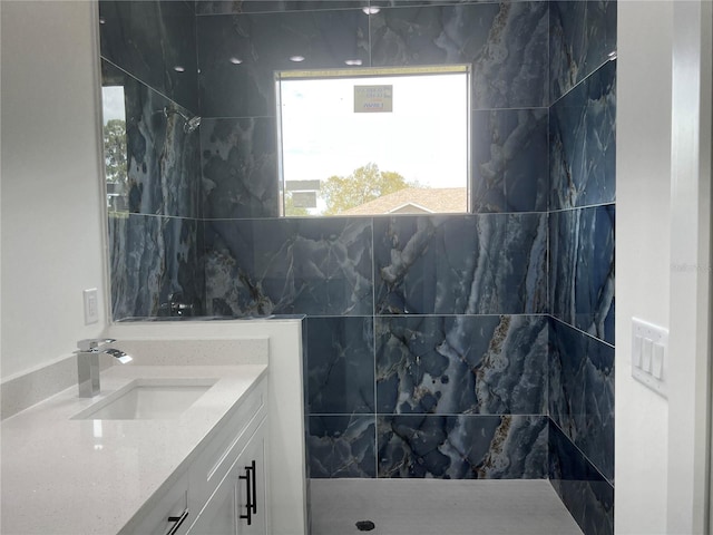 bathroom with a tile shower and vanity