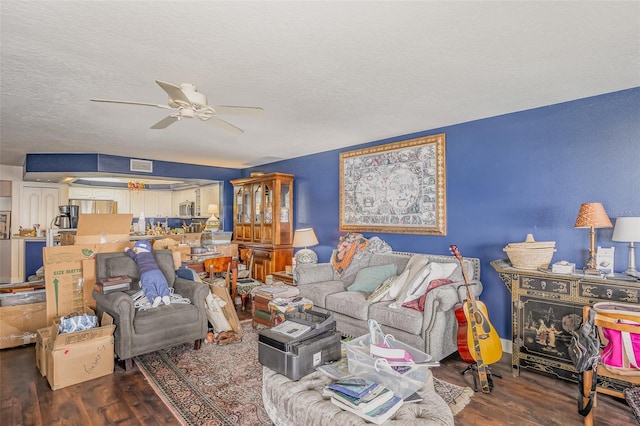 living area featuring dark wood-style floors, ceiling fan, and a textured ceiling