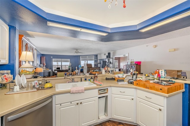 kitchen with dishwasher, open floor plan, a sink, and white cabinets