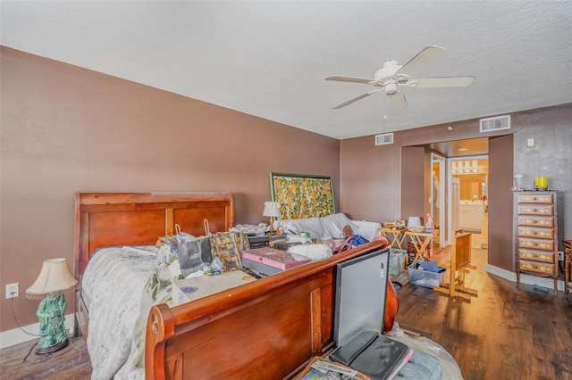 bedroom with dark wood-style floors, ceiling fan, visible vents, and a textured ceiling