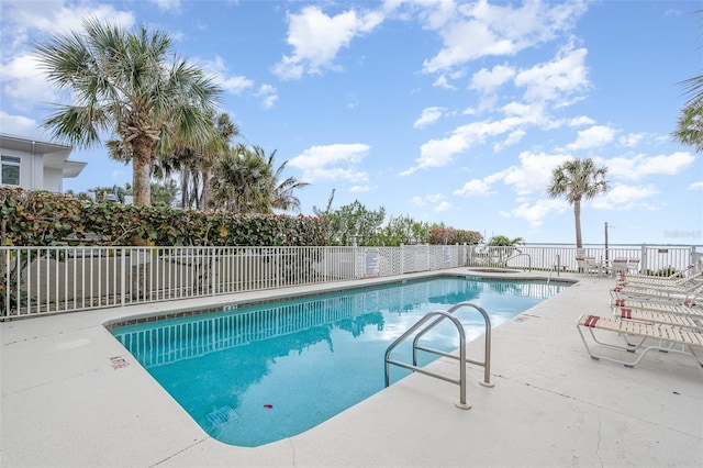 community pool with a patio area and fence