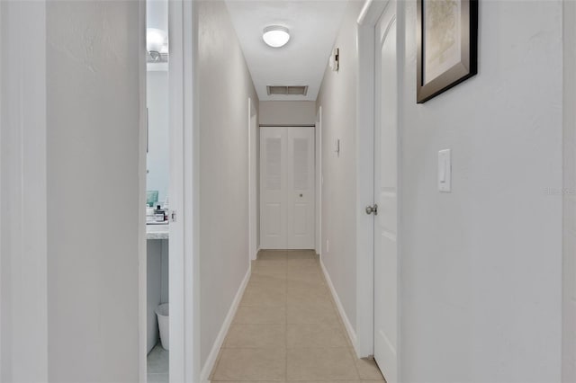 corridor featuring visible vents, baseboards, and light tile patterned flooring