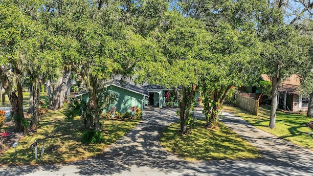 obstructed view of property featuring concrete driveway, a front lawn, and fence